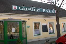 Exterior view of an inn with yellow facade and green sign 'Gasthof Paus'.