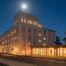 An illuminated building at night with a bright moon in the sky.