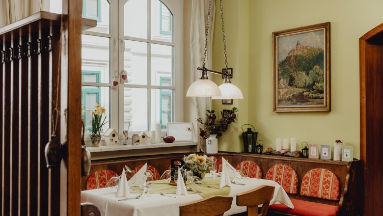 Cozy dining room with table setting, wooden furniture and decorations.