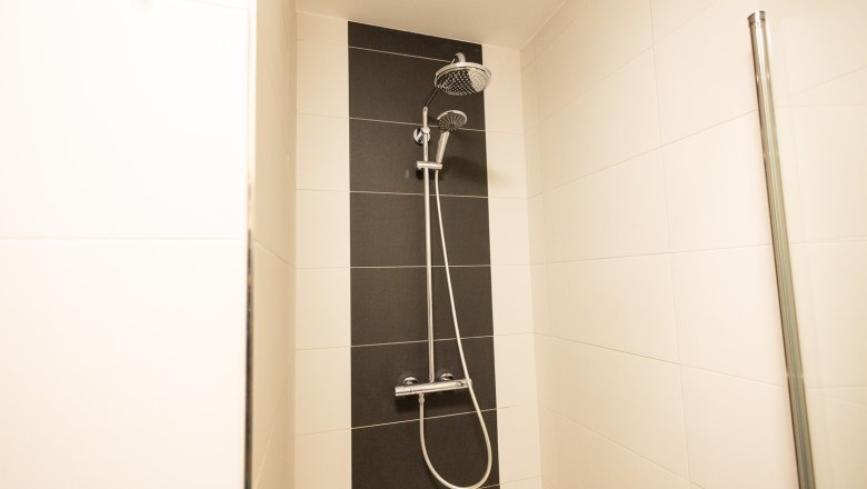 Modern shower with black and white tiled wall.