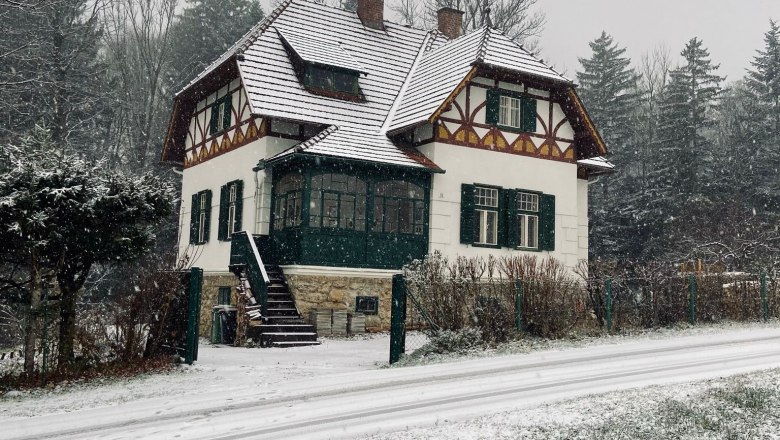 Orlet on the Rax, © Sofia Orlet A snow-covered house in traditional style with green shutters, surrounded by trees and a snow-covered street.
