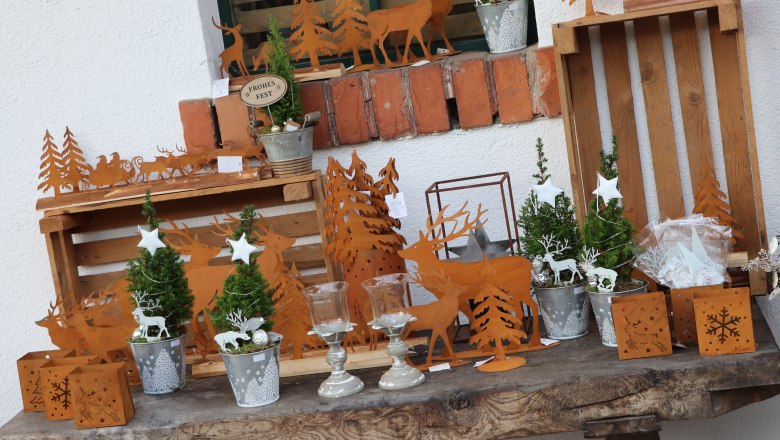 Christmas decoration with metal reindeer and Christmas tree motifs on a wooden table.
