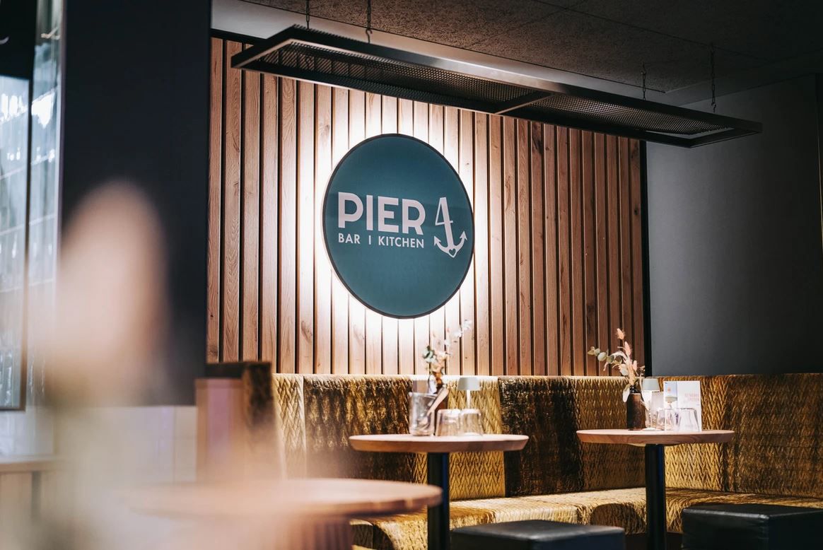 Interior view of the Pier 4 restaurant with wooden wall and logo.