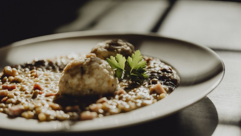 Close-up of a plate with lentil dish and dumplings, garnished with parsley.