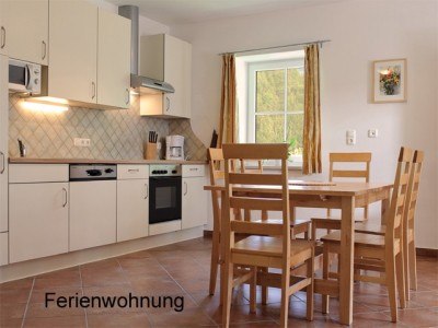 Bright kitchen with dining table and chairs, window with curtains, tiled floor.