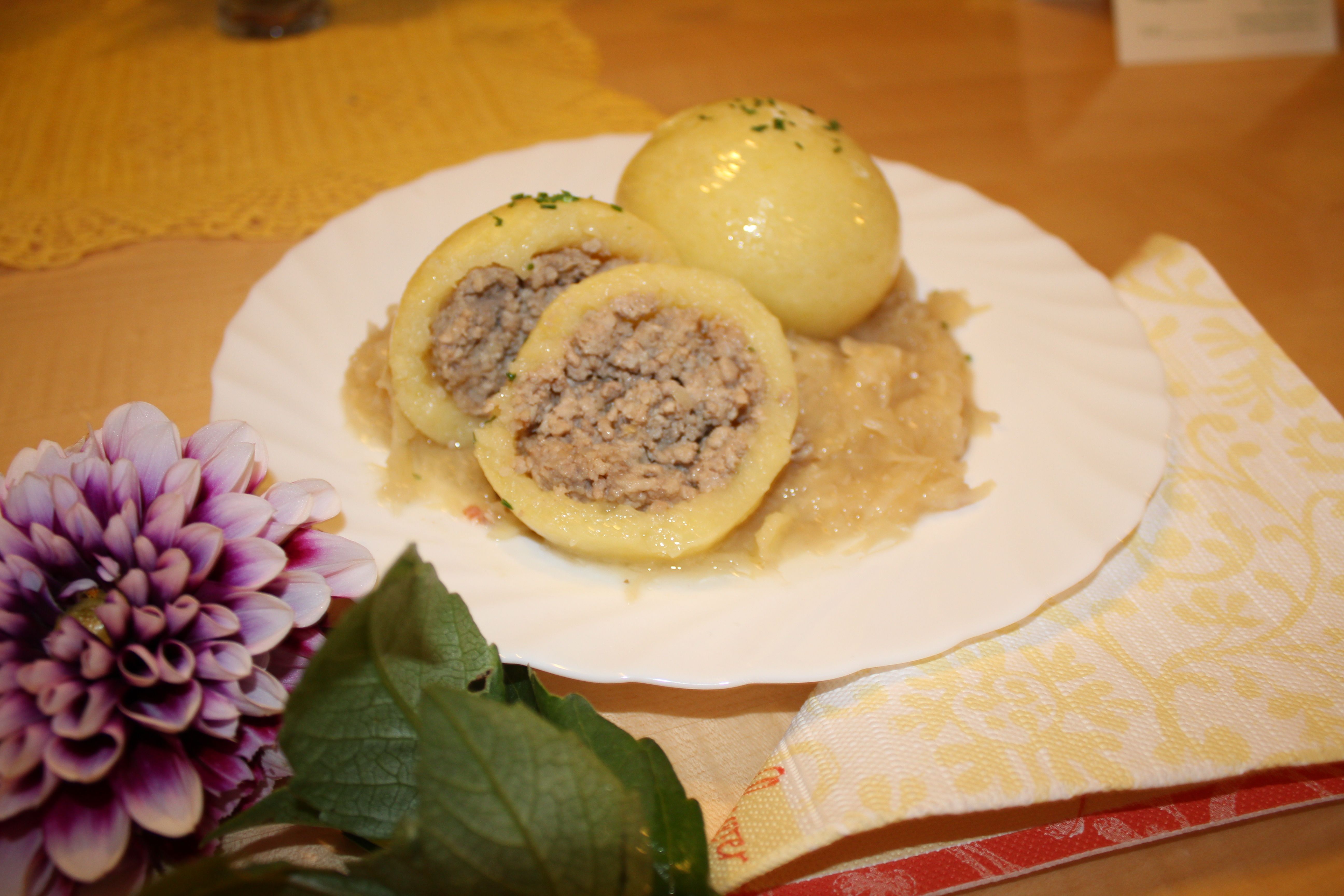 A plate of Waldviertel meat dumplings on sauerkraut, decorated with a flower.