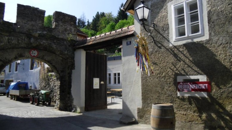 Entrance to a traditional wine tavern with archway and sign.