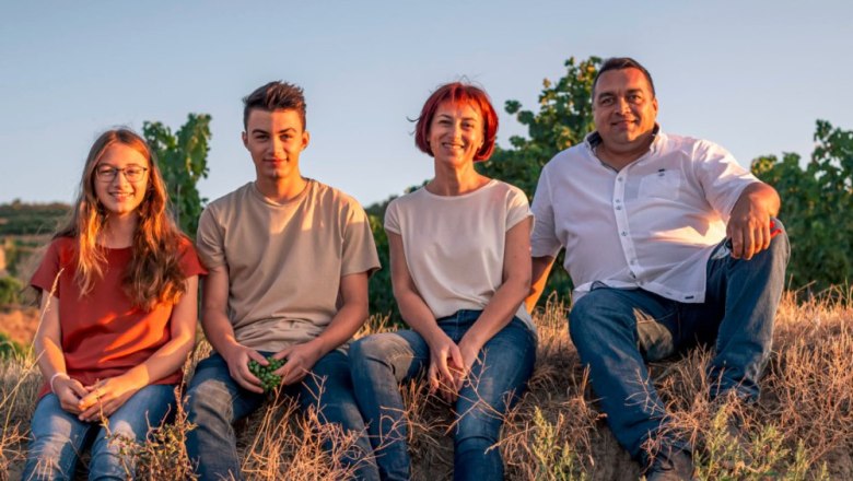 Four people sitting in a field at sunset.
