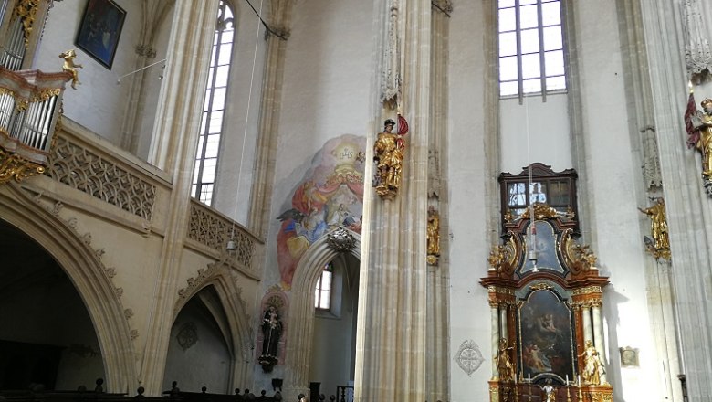 Interior view of the Piarist Church with altar, frescoes and high windows.
