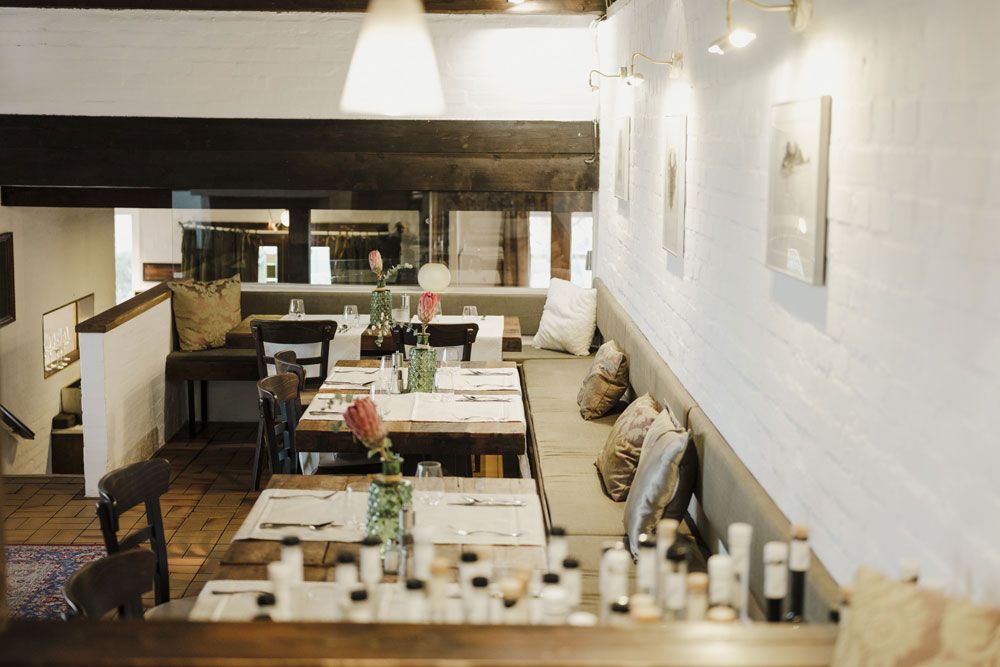 Cozy restaurant with wooden tables, cushions and subtle lighting.