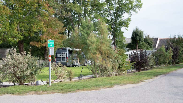 Campsite with motorhome and trees in the background.