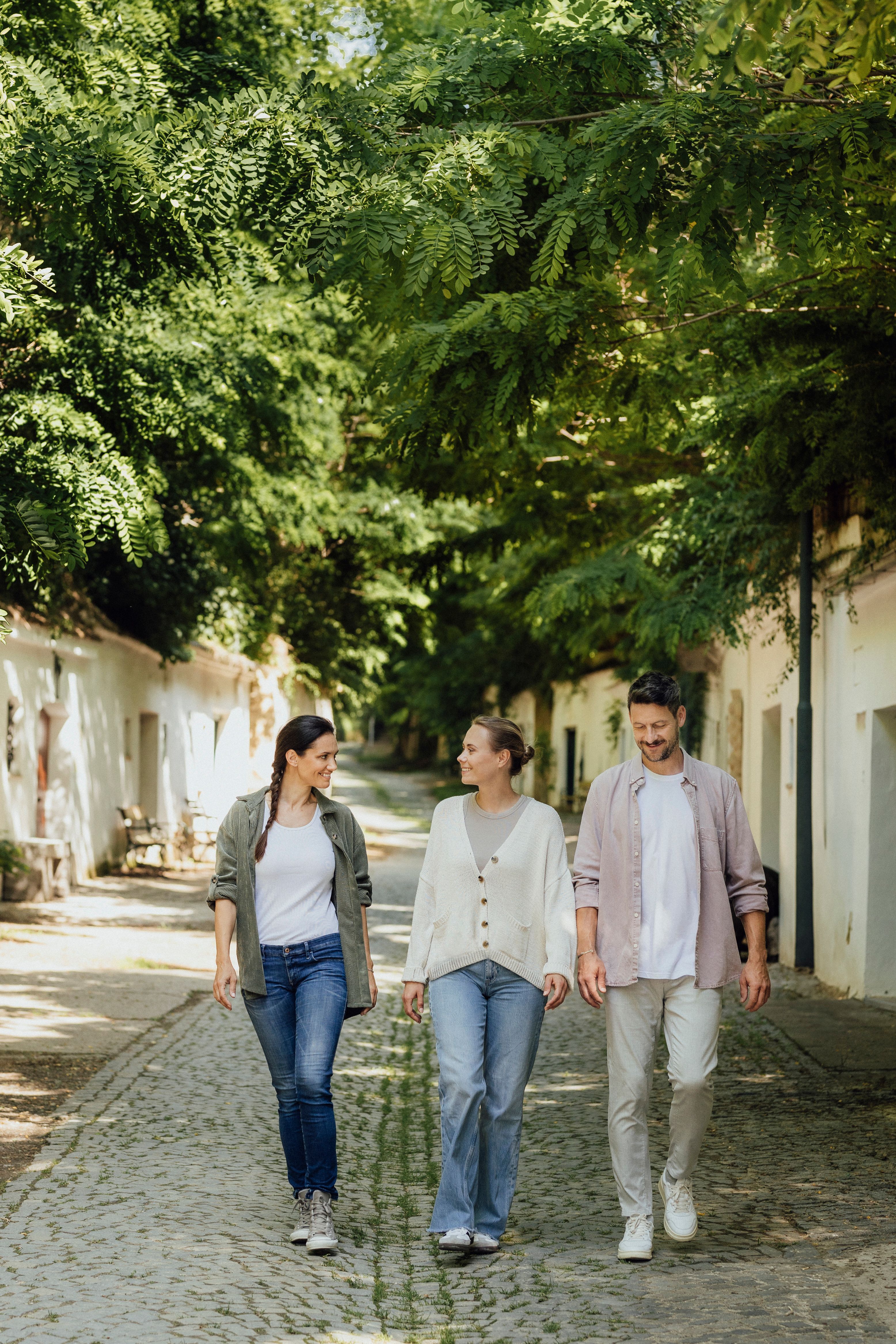 Three people are walking along a tree-lined path in Poysdorf.