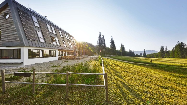 Knofeleben Naturefriends House on the Gahns, © Wiener Alpen / Bene Croy Naturfreundehaus Knofeleben in a sunny mountain landscape with solar panels on the roof.