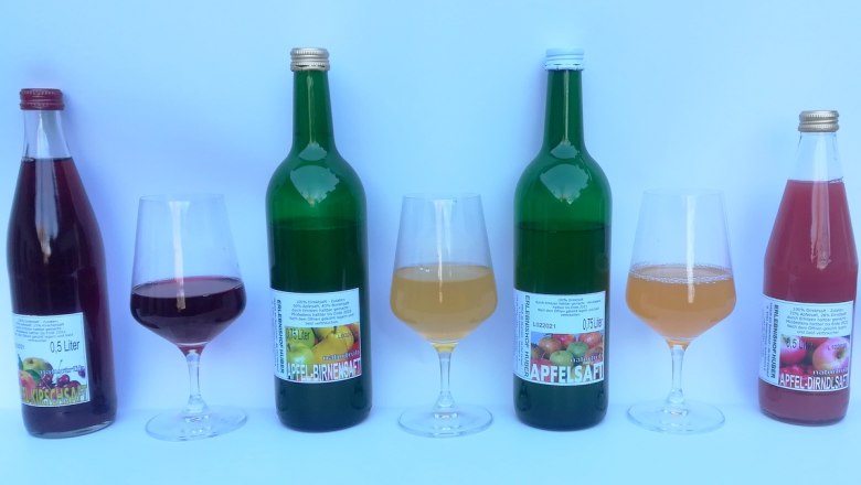 Various bottles and glasses with juices on a white background.