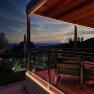 Evening atmosphere on a terrace with a view of the mountains and a garden.