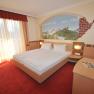 Double room with double bed, wall painting and red carpet.