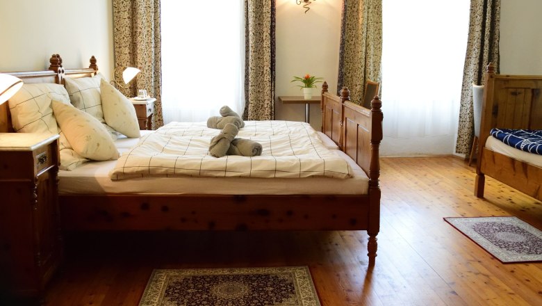 Cozy bedroom with wooden bed, bedside tables and decorative towels on the bed.