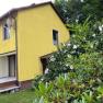 Yellow house with terrace and flowering shrubs in the foreground.