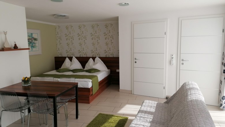 Room with double bed and two white entrance doors