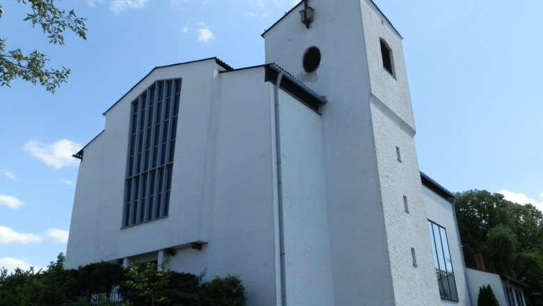 White church with tower and cross against a blue sky.