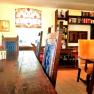 A cozy breakfast room with wooden table, blue chairs, bookshelf and decorative window.