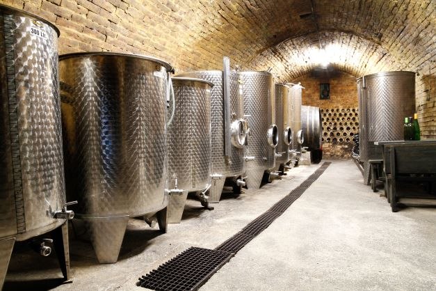 A wine cellar with large stainless steel tanks and brick vaults.