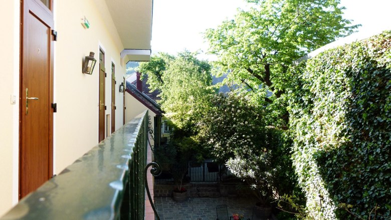View from a balcony onto a green inner courtyard with trees and climbing plants.
