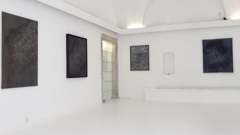 Interior view of a gallery with abstract paintings on white walls.