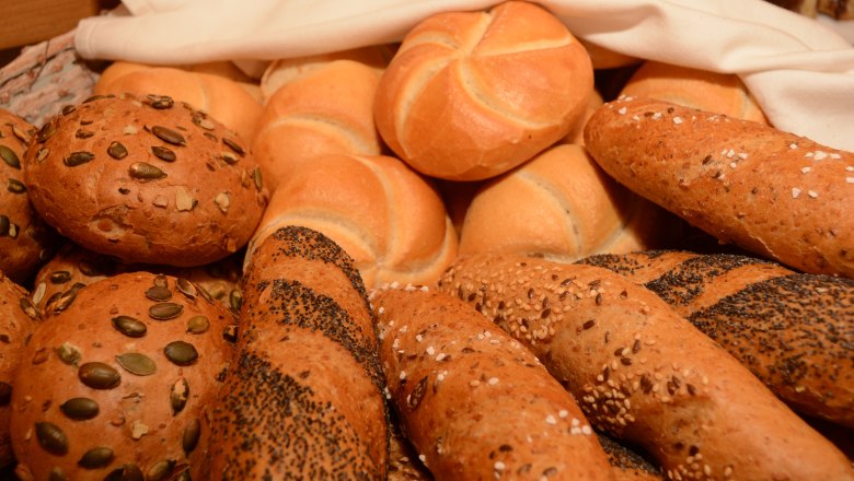 Various types of breakfast pastries, including rolls and baguettes with grains.