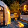 A modern chalet with a terrace and a transparent dome tent in the forest at dusk.