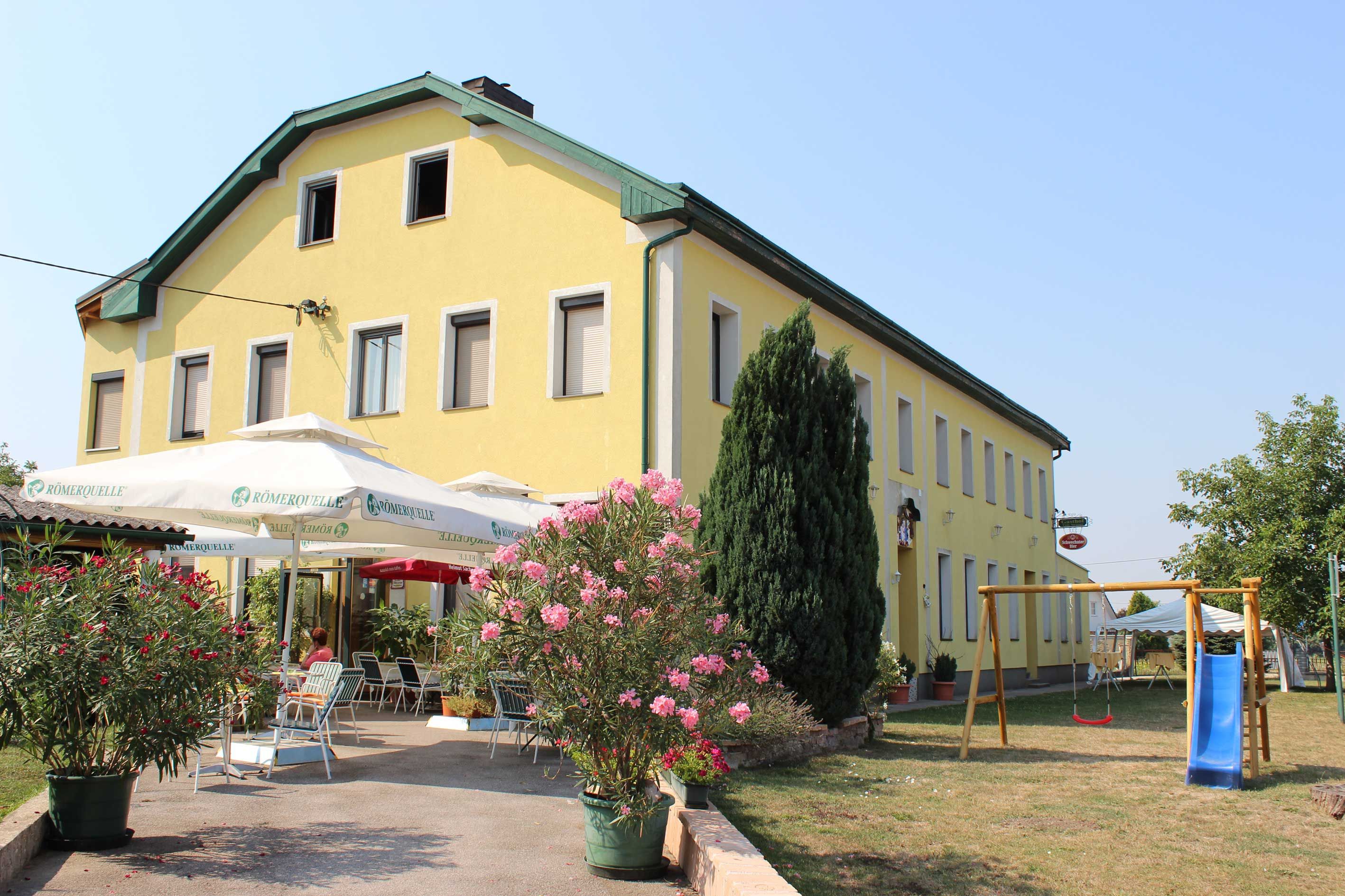 Yellow building with terrace and playground in the foreground.