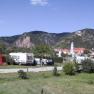 Campsite with caravans and tents in front of a mountain landscape and a church in the background.