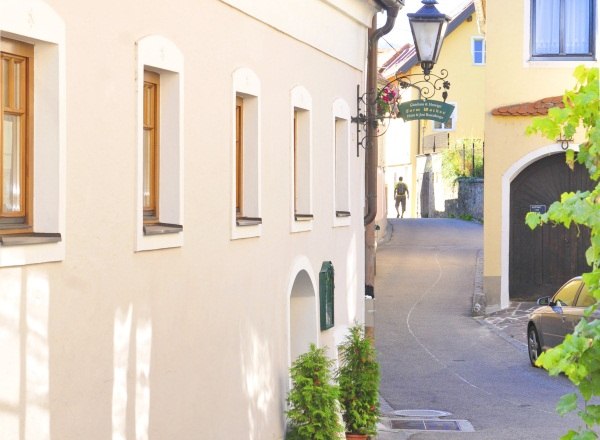 Narrow alley in the Wachau with yellow houses and a lantern.