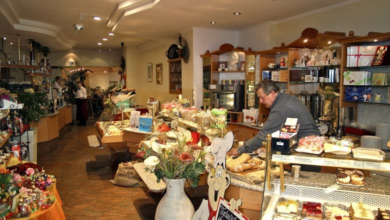 Interior view of a cozy café with a counter full of cakes and pastries.