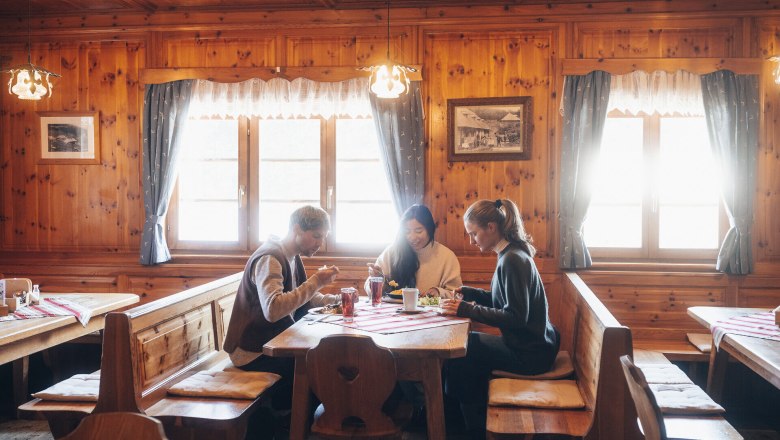 In the cozy atmosphere of a traditional hut, guests enjoy delicious food and the company of friends. The warm wooden interior and the soft rays of light create an inviting atmosphere that invites you to linger. Here, winter in the Vienna Alps becomes an unforgettable experience.