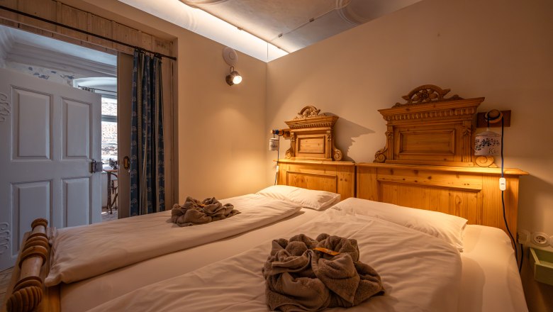 Cozy bedroom with two single beds and wooden decorations, warmly lit.