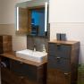 Modern bathroom with wooden cabinets, washbasin and illuminated mirror.