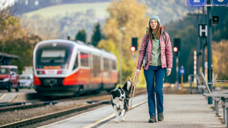 Woman with dog at Aspang station, train in the background.