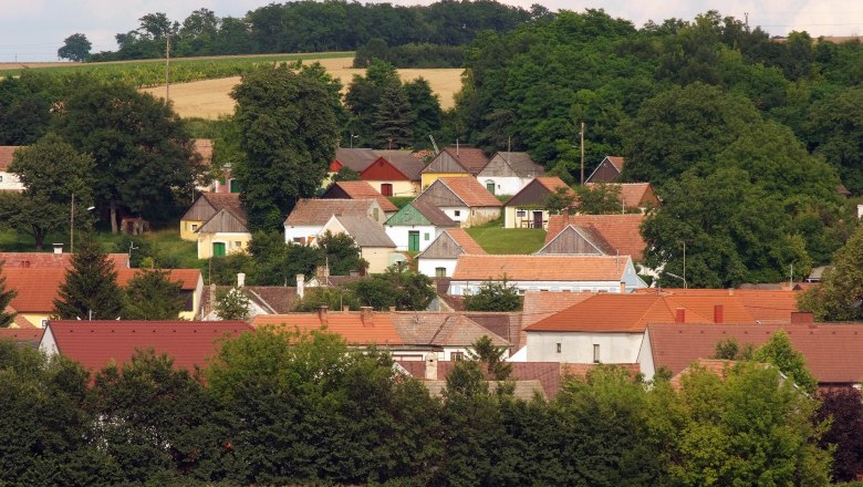 View of a village with colorful houses and a green landscape in the background.