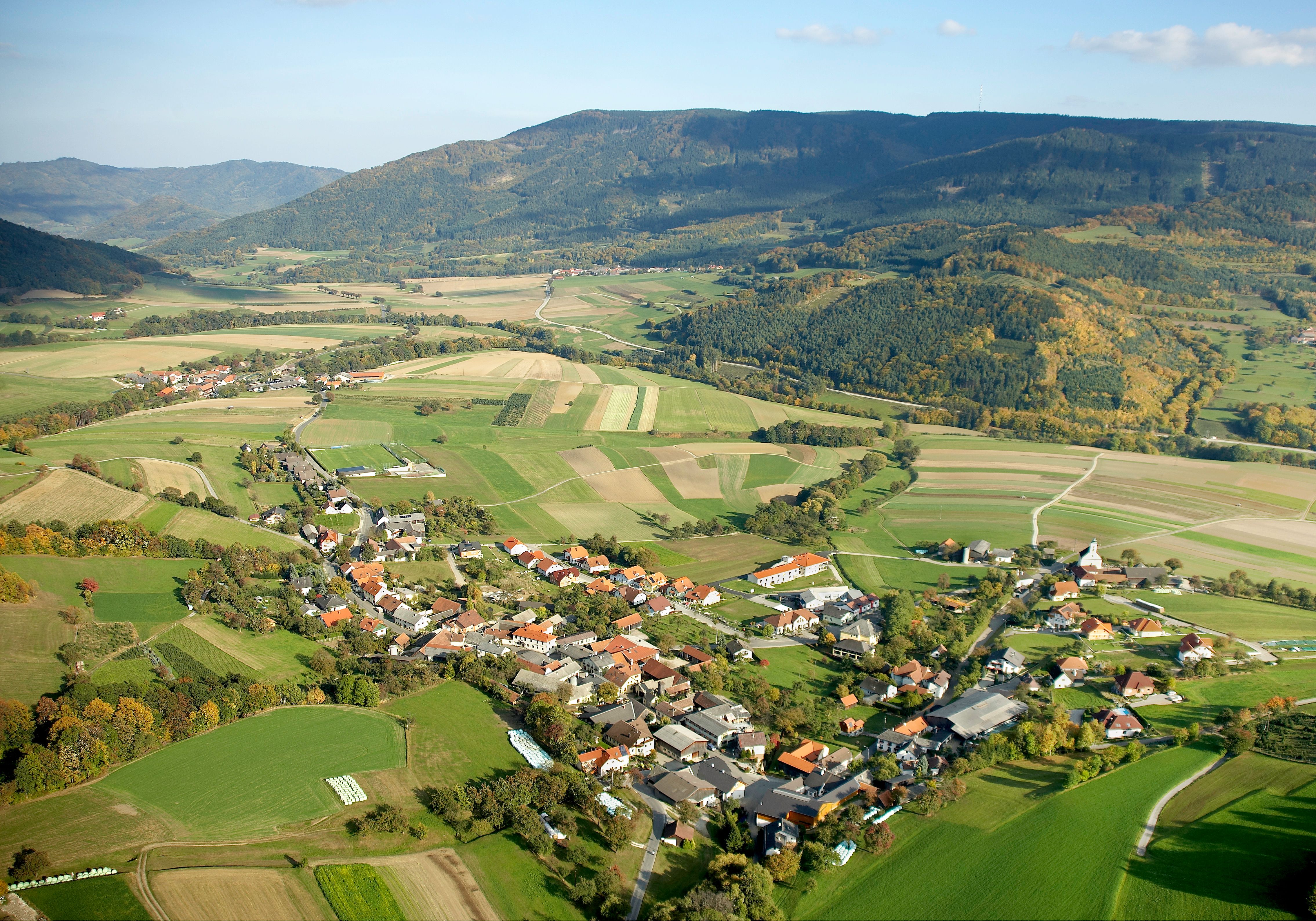 Aerial view of a rural community with fields and hills in the background.