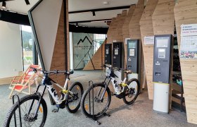 Interior view of an e-MTB rental shop with bikes and ticket machines.