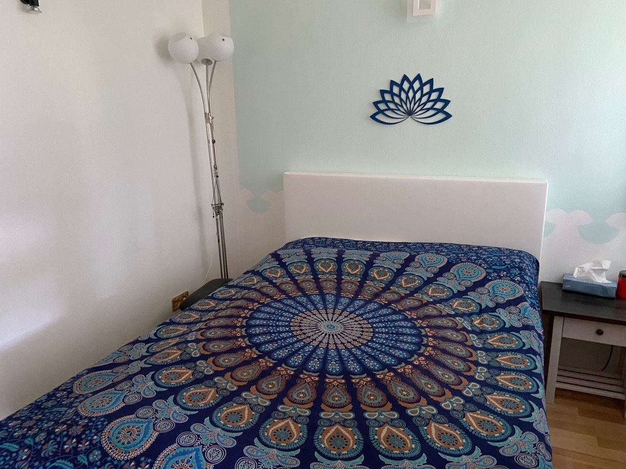 Bedroom with waterbed, colorful comforter and lotus wall decoration.