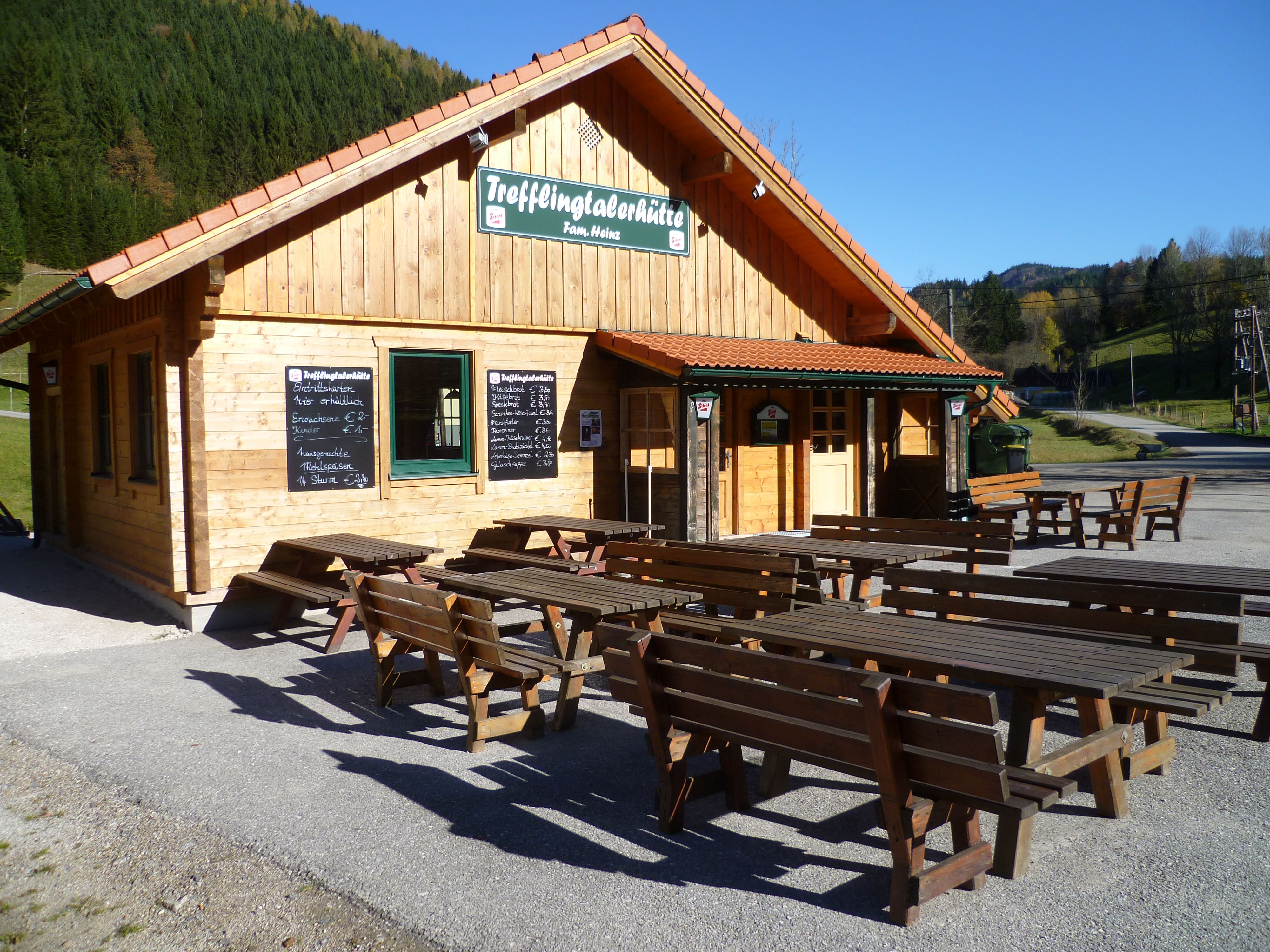 Wooden hut with outdoor tables, sunny day.