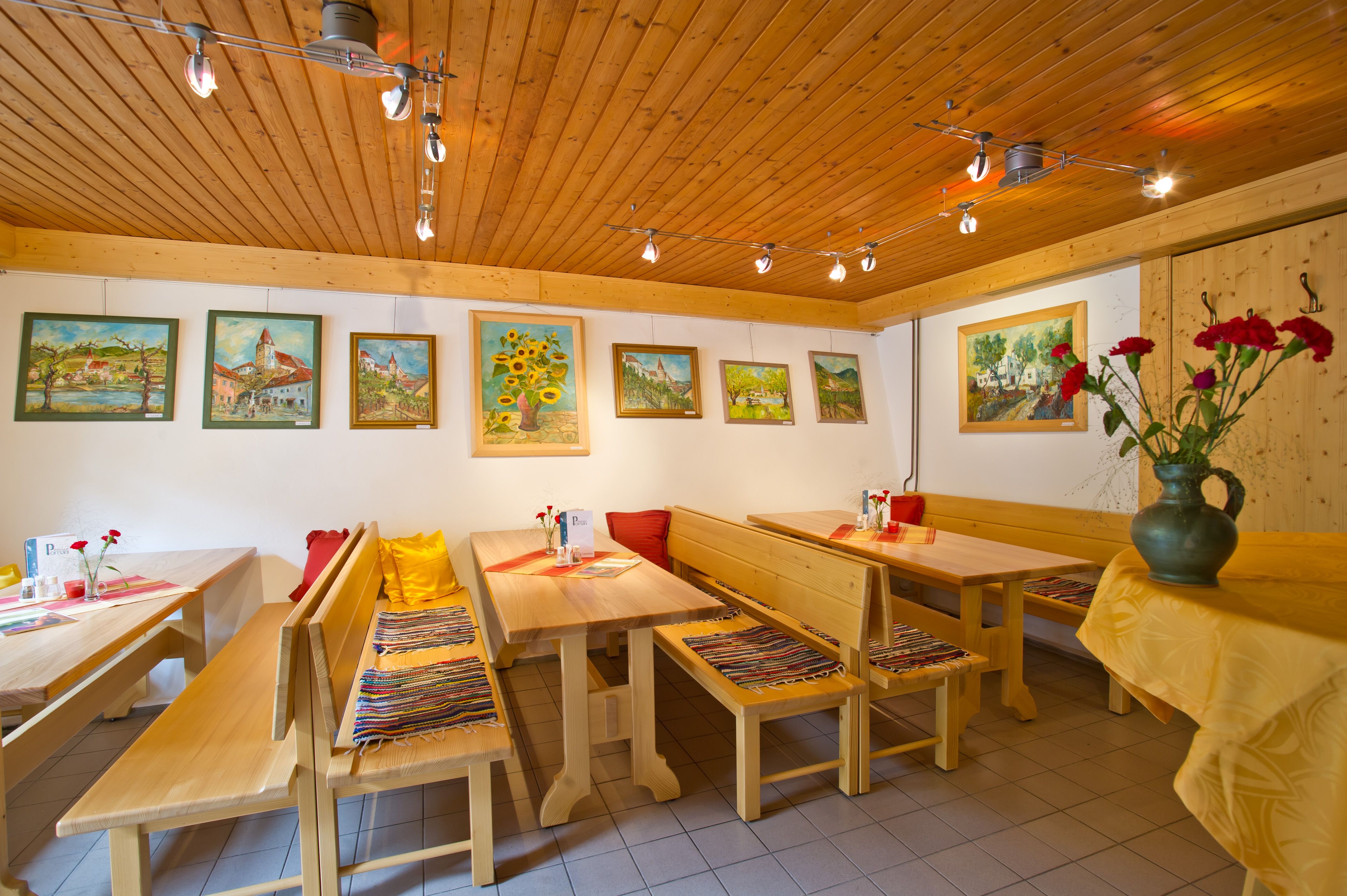 Interior view of a wine tavern with wooden furniture and paintings on the wall.