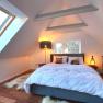 Modern bedroom with sloping ceiling, large bed, skylight and stylish lighting.