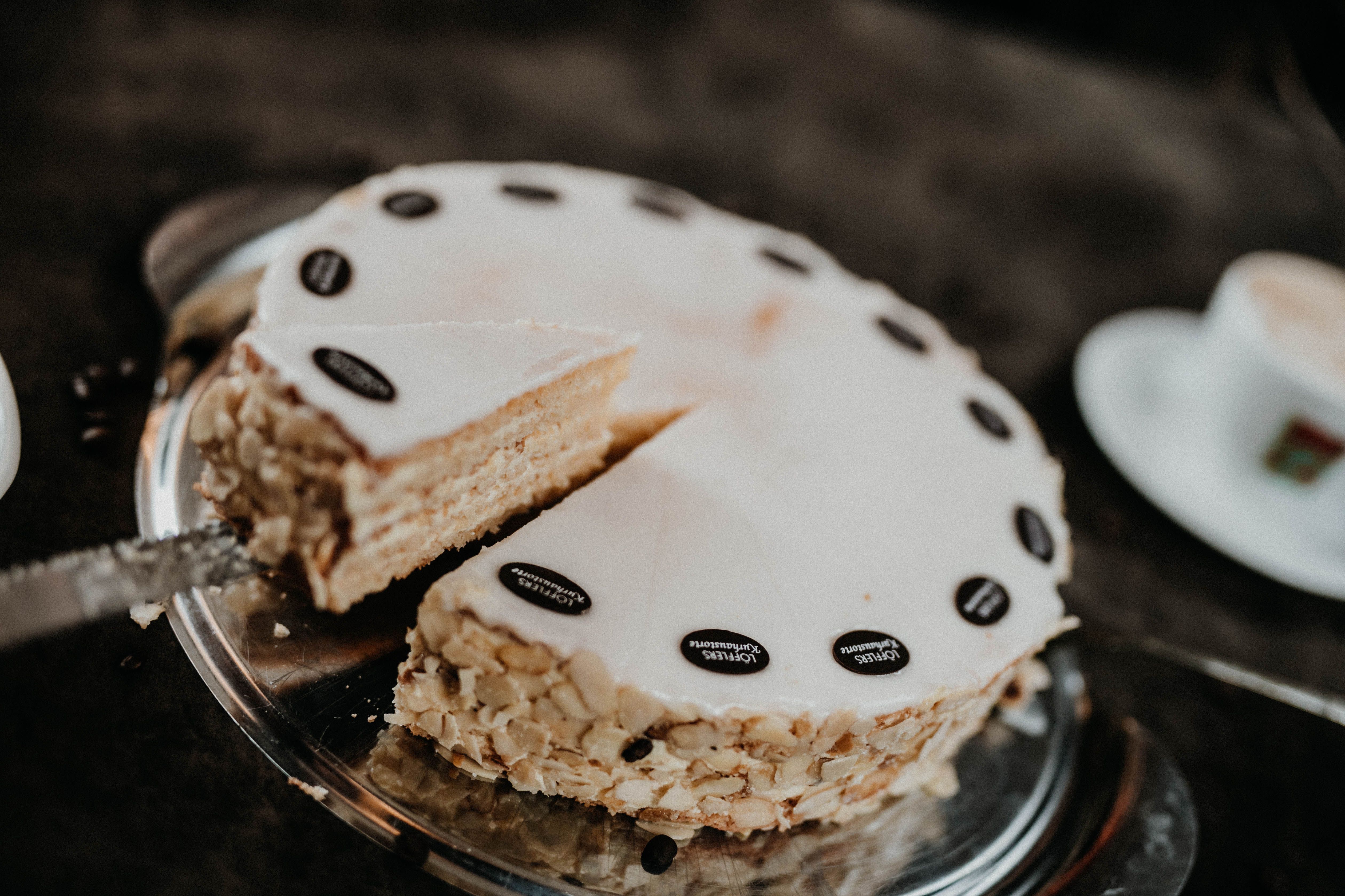 A cut cake with almonds and chocolate decoration on a tray.