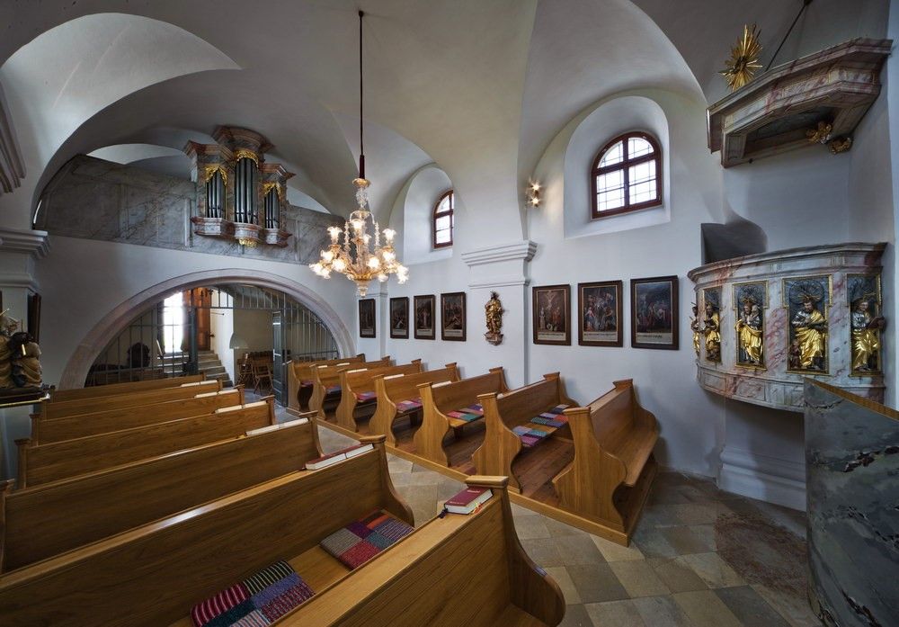 Interior view of a small church with wooden pews, a pulpit and an organ in the gallery.