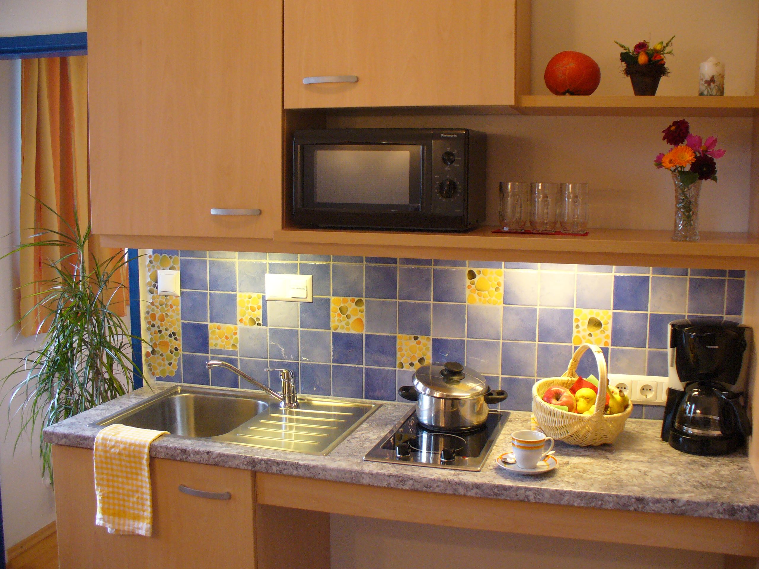 Kitchenette with sink, stove, microwave and decorations.