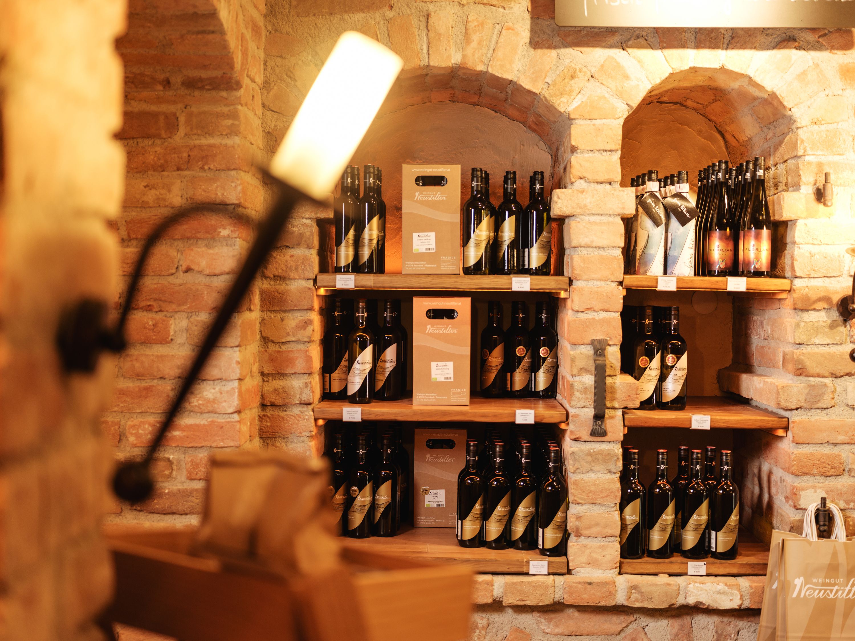 Wine bottles in a rustic cellar shelf made of bricks.