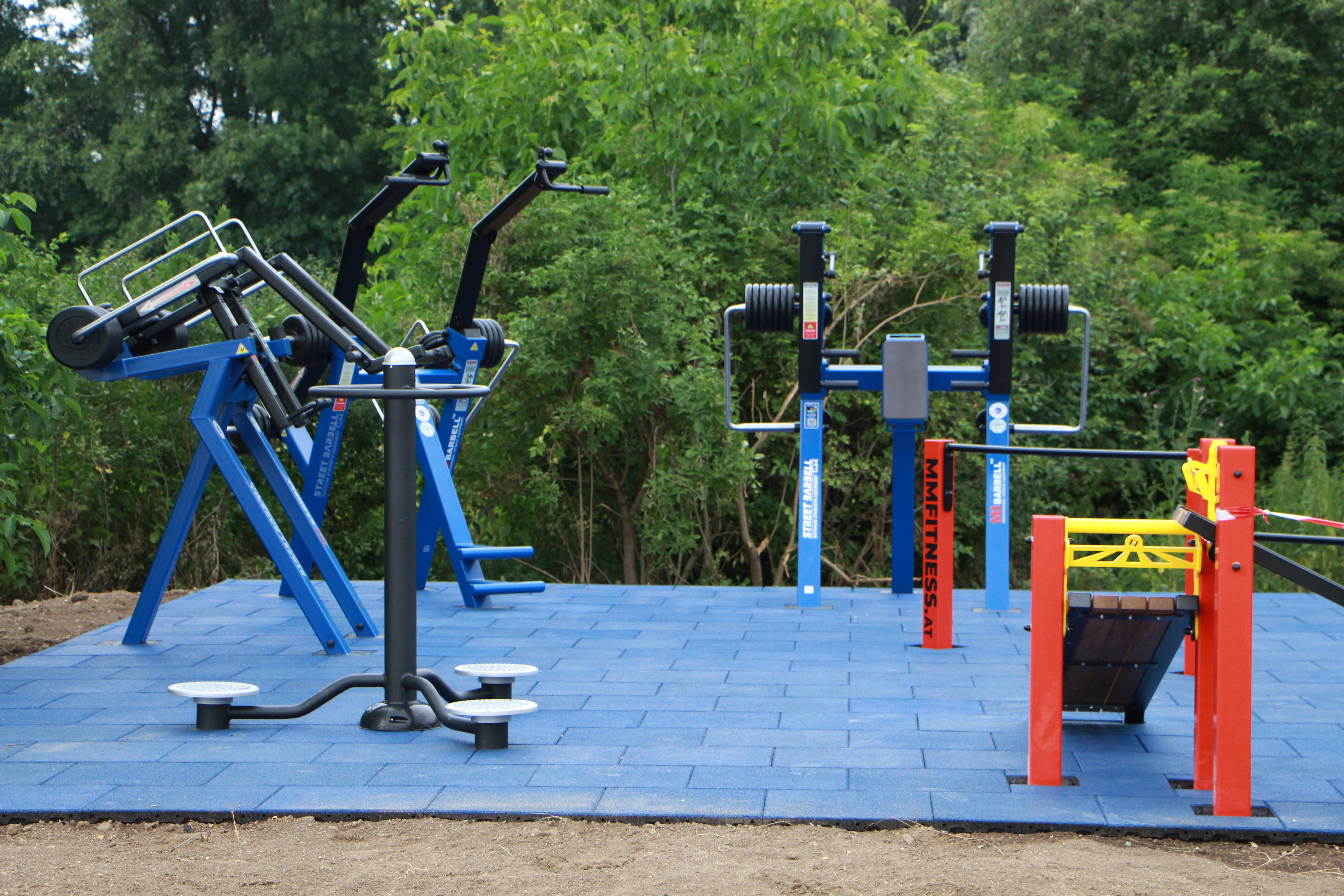 Outdoor fitness equipment on blue outdoor floor tiles.